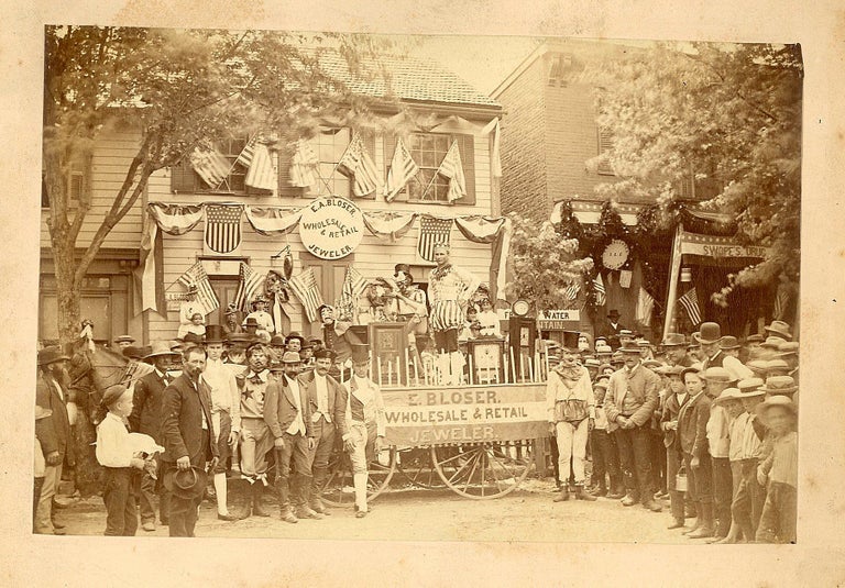 Item #29001745 Photograph of Group of Men in Costume, Surrounding the Parade Wagon of E. A. Bloser Wholesale & Retail Jeweler